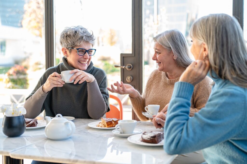 A group of senior women chatting & enjoying their time together at an Assisted Living community.
