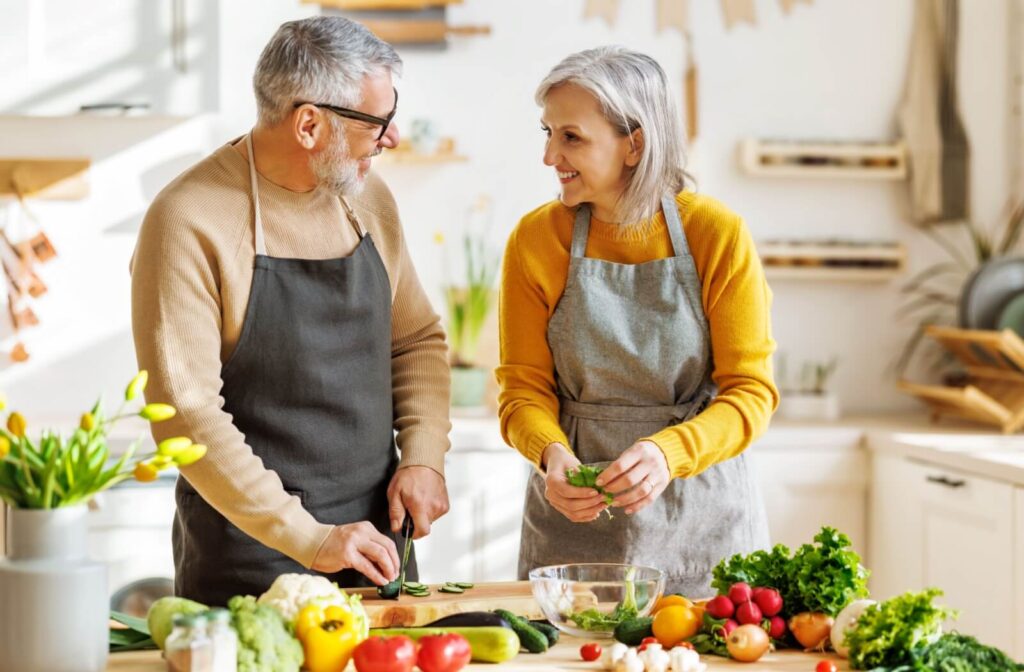 A happy senior couple prepares a colorful meal, filled with vegetables to support their cognitive function and overall health.