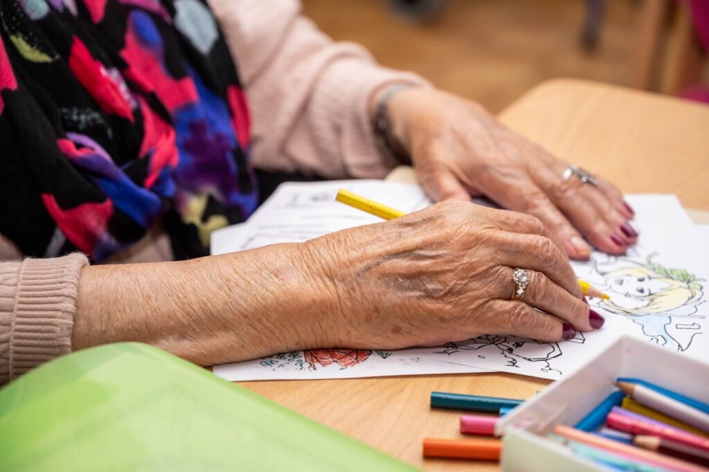 Close up view of a senior woman's hands as she colours a colouring page.