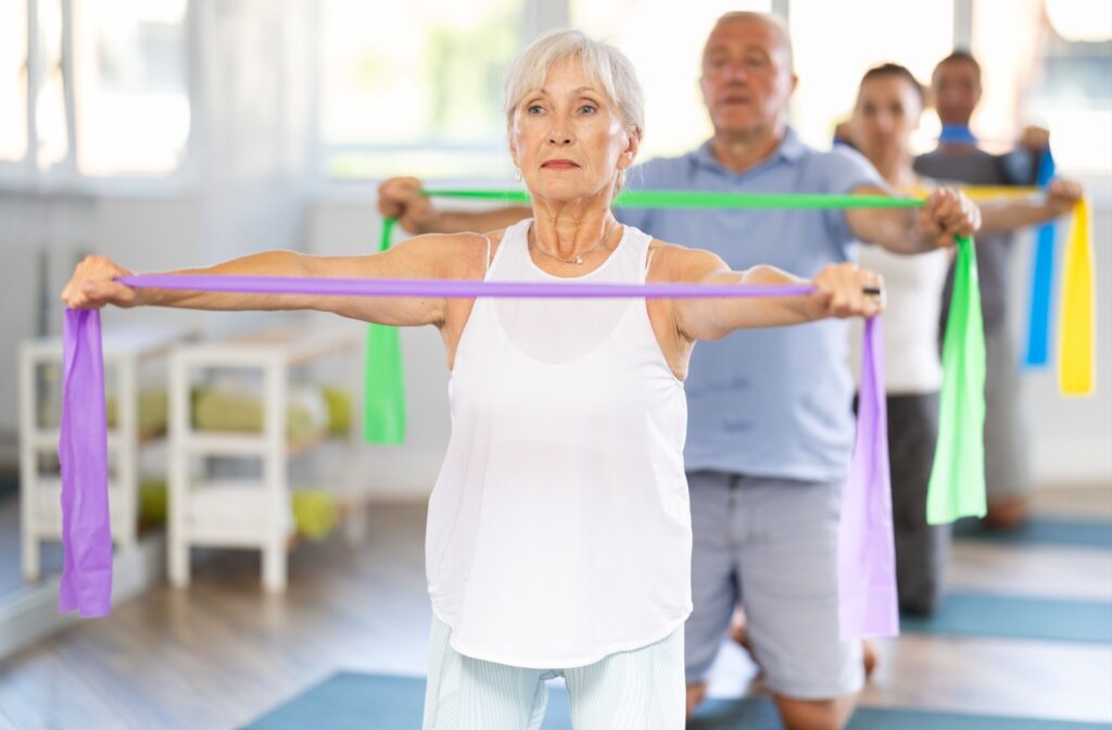 Seniors using resistance band training in a bright gym setting to help improve posture and overall health.