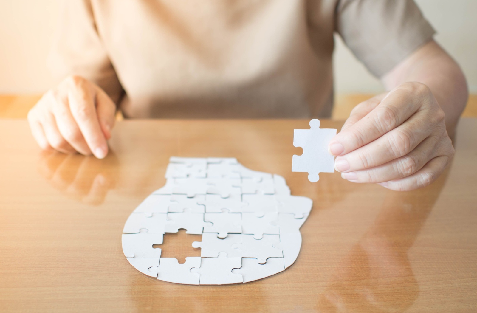 Senior person completing a head-shaped puzzle as part of a memory exercise.