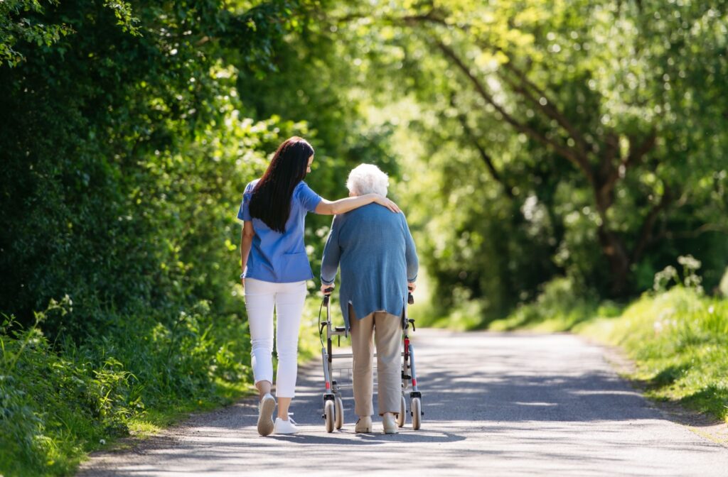 Woman walking with a nurse along a path in a memory care facility.