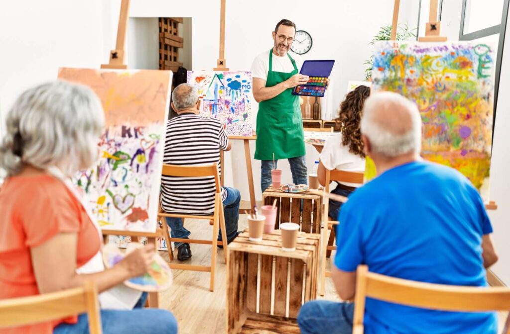 A group of seniors listen to their instructor during an abstract painting class offered by their senior living community