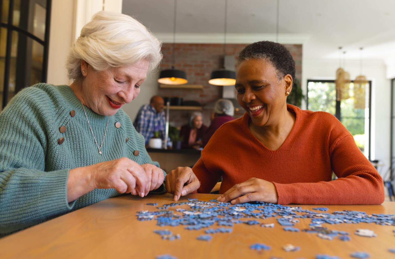 Seniors gathered around a table smiling and playing cards together