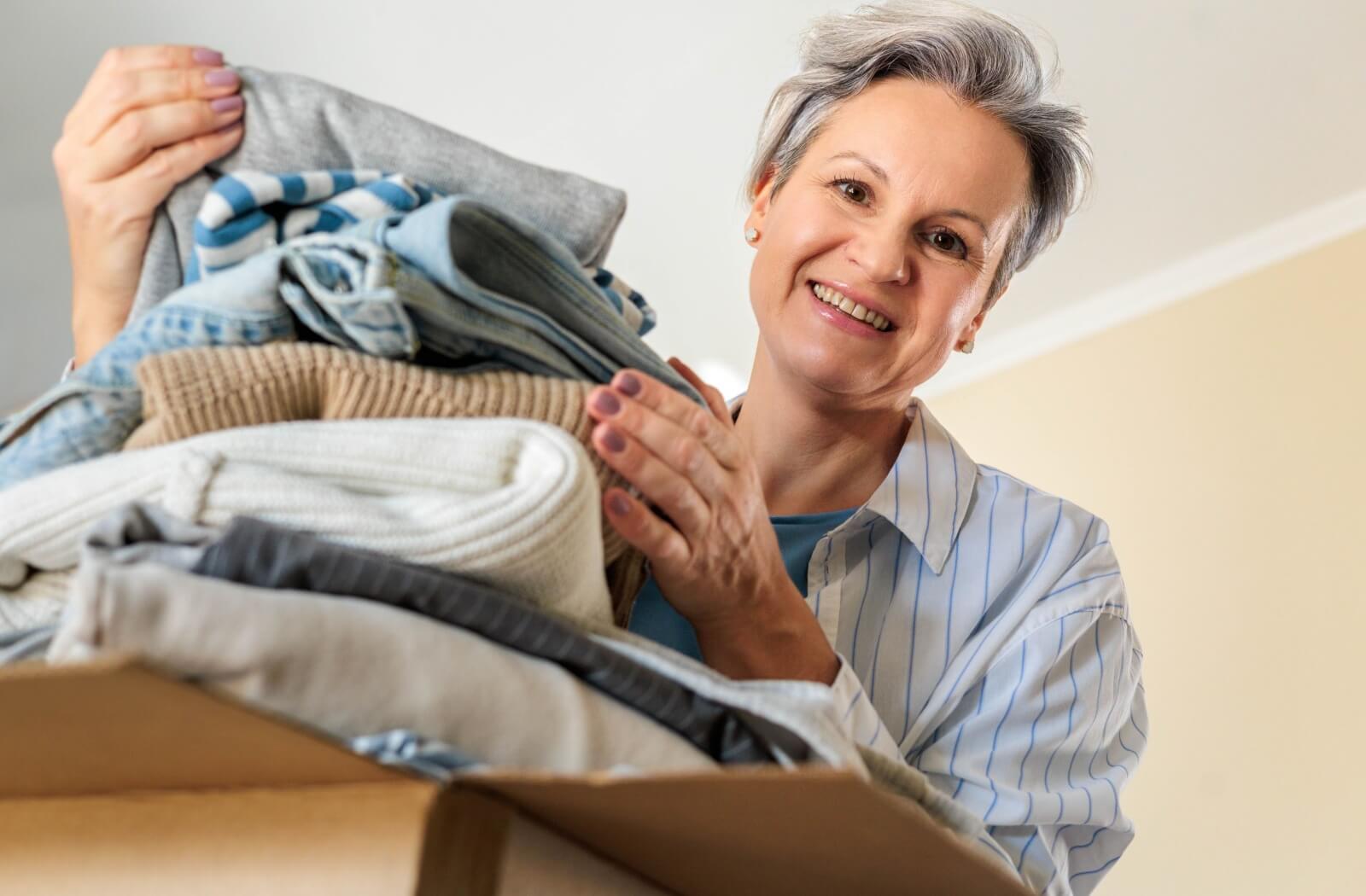 Senior folding clothes into box while downsizing before assisted living